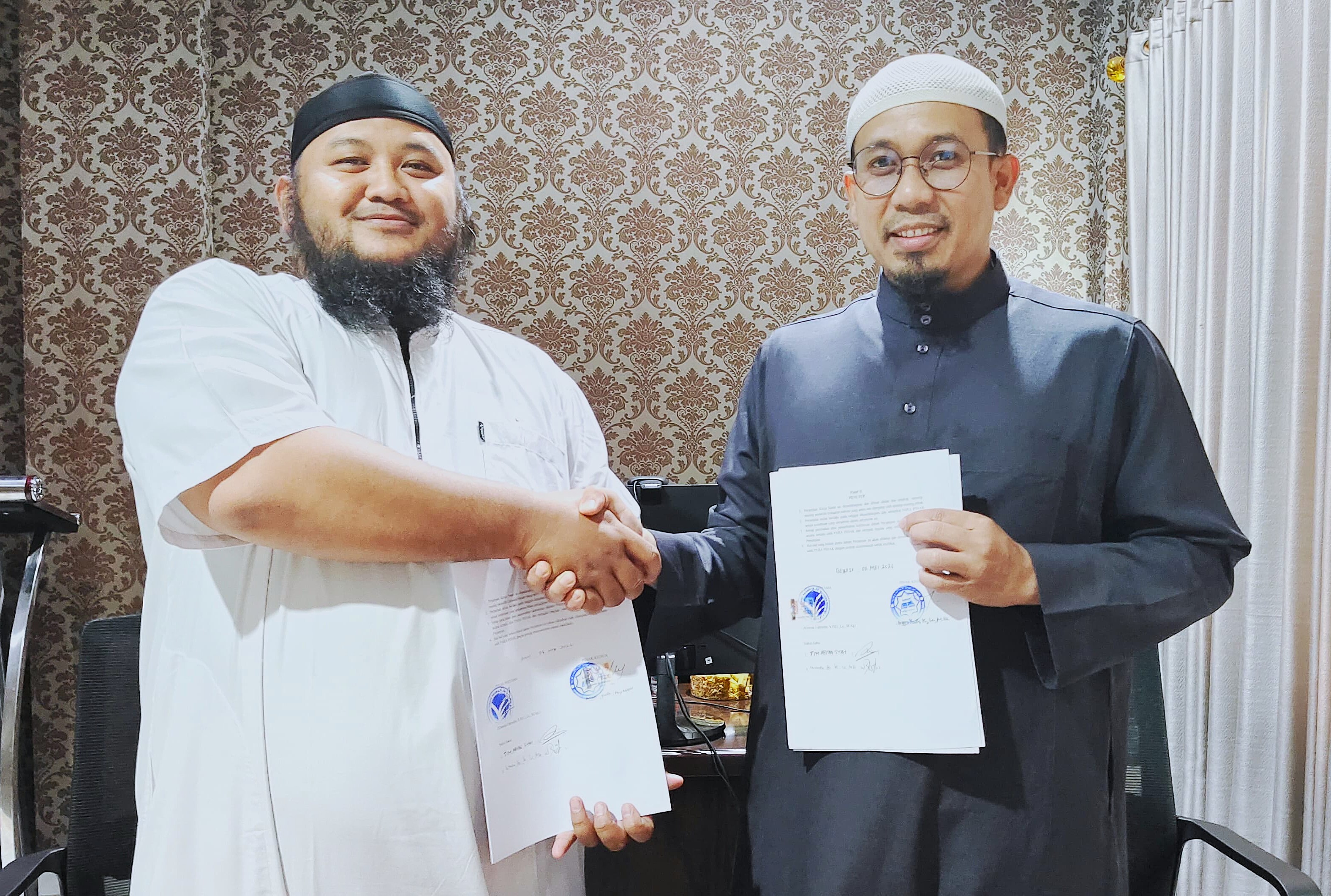 Perwakilan STAI Mutiara Bangsa dan LSIA Indonesia berjabat tangan sambil menunjukkan dokumen Memorandum of Agreement